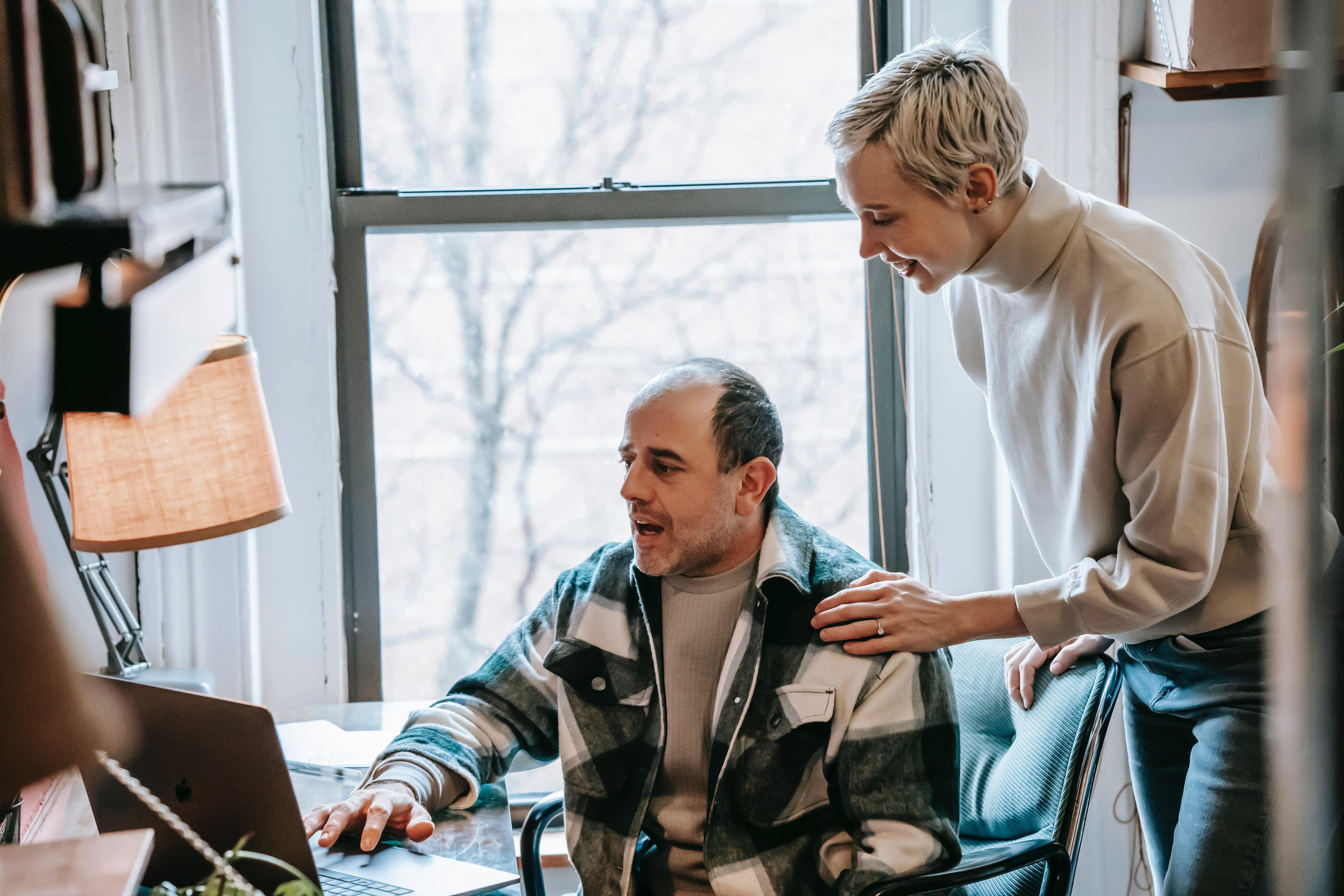 Homme sur son ordinateur et femme lui touchant l'épaule